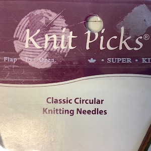 Puede incluir: Un primer plano de un paquete de agujas circulares clásicas Knit Picks Super King. El paquete es morado y blanco con el logotipo de Knit Picks y las palabras "Super King" impresas en él. Las agujas son visibles a través del embalaje de plástico.