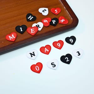 Aplique bordado personalizado em formato de coração com inicial, ideal para decoração de casamentos e festas.