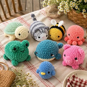 May include: A collection of eight small, plush crochet animals including a green turtle, a grey striped cat, a yellow and black bee, a pink octopus, a green frog, a blue whale, a pink pig, and a small blue bird, all with black eyes.