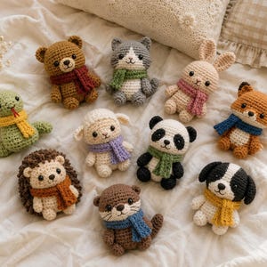 May include: A collection of nine small, handmade crochet stuffed animals, including a bear, cat, rabbit, fox, snake, sheep, panda, hedgehog, otter, and dog. Each animal is wearing a small, colorful knitted scarf around its neck.