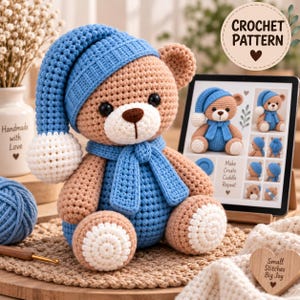 Può includere: Un orsacchiotto color marrone chiaro realizzato all'uncinetto che indossa un berretto da notte blu con un pompon bianco e una sciarpa blu abbinata. L'orso ha il muso bianco e macchie bianche sui piedi. Un tablet mostra il modello CROCHET PATTERN.