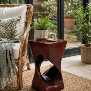 May include: A dark brown wooden side table with a twisted, hourglass-shaped base and a flat square top. The table features a smooth, polished finish with visible wood grain and a hollow centre section, providing a sturdy surface for small items.