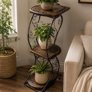 May include: A three-tiered plant stand featuring dark brown wooden shelves with carved edges and a black metal frame with decorative scrollwork. The stand holds three potted green plants, one on each level, arranged in a vertical, S-shaped structure.
