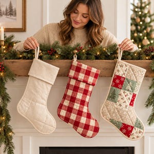 May include: Three Christmas stockings hanging in a row. The first is solid cream-colored fabric with a quilted texture. The second features a red and white buffalo check pattern. The third is a patchwork design with green and red snowflake motifs.