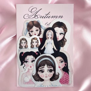 Puede incluir: Una colección de pegatinas ilustradas con retratos estilizados de mujeres con ojos grandes y varios peinados. Las pegatinas están dispuestas sobre un fondo rosa con el texto "Autumn 1st" en escritura elegante.