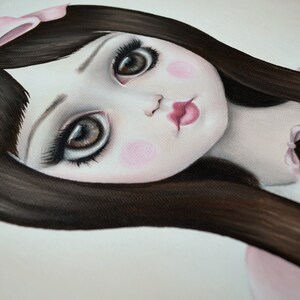 May include: A painting of a doll with long dark hair, wearing a pink bow and a pink dress. The doll has large brown eyes and rosy cheeks. A smaller doll is visible in the background.