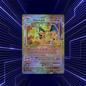 May include: A holographic Charizard trading card featuring the orange dragon-like creature with wings, 120 HP, and the Energy Burn power. The card displays text detailing its Fire Spin attack, weakness, resistance, and retreat cost, with a 25th anniversary logo.