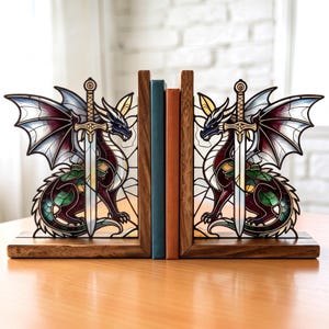 Puede incluir: Un par de sujetalibros de madera con diseños de dragón y espada al estilo de vidrieras. Cada dragón está representado en tonos rojo oscuro, verde y blanco, con una espada central. Los sujetalibros sostienen dos libros con lomos azul y naranja.