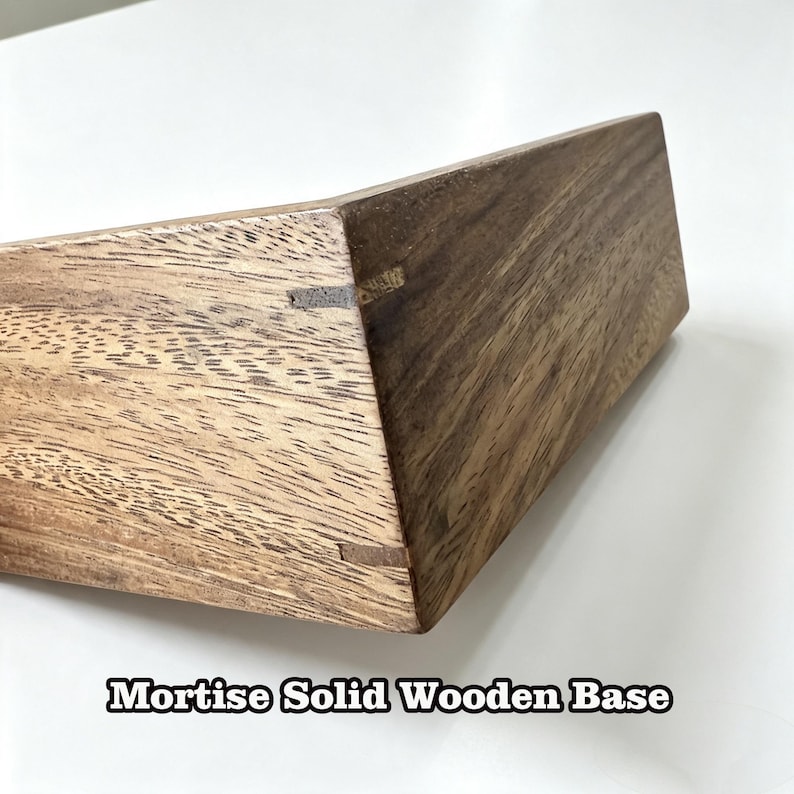Puede incluir: Una base de madera maciza con un patr&oacute;n de veta de madera marr&oacute;n natural y detalles visibles de carpinter&iacute;a de mortaja. El objeto est&aacute; inclinado para mostrar la construcci&oacute;n de la esquina y el texto Mortise Solid Wooden Base aparece debajo.