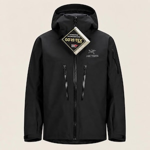 Könnte beinhalten: Eine schwarze Kapuzenjacke mit durchgehendem Frontreißverschluss, zwei großen vertikalen Brusttaschen mit schwarzen Reißverschlüssen und einer kleineren Reißverschlusstasche am linken Ärmel. Ein weißes Arc'teryx-Logo und ein Gore-Tex-Etikett.