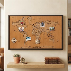 May include: A rectangular wooden world map wall art piece with a dark frame, featuring laser-cut continents and country names. The map includes a compass rose and five small photographs attached with colorful push pins to various locations.