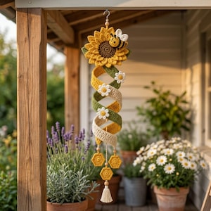 May include: A hanging crochet decoration featuring a large yellow sunflower with a brown center and a small bee attached. Below the flower is a spiral strip in alternating green and cream colors, accented with white daisies and three yellow hexagons.