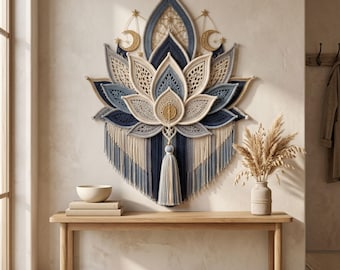 May include: A large macrame wall hanging shaped like a lotus flower in shades of navy blue, light blue, and cream. The design features intricate knotted patterns, gold-toned crescent moon and star accents, and a central tassel with fringe.
