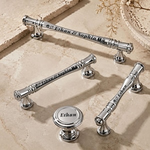 May include: A set of three polished chrome cabinet pulls and one matching round cabinet knob. Two pulls are engraved with the text Ethan & Sophia, while one pull and the round knob are engraved with the name Ethan, each featuring small floral accents.