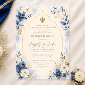 Pode incluir: Um cartão de convite retangular com fundo creme e detalhes florais em aguarela azul e dourada. O centro apresenta uma moldura dourada arqueada contendo o símbolo Khanda, texto em punjabi e detalhes em inglês para uma cerimónia Sri Akhand Path Sahib.