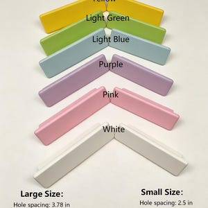 May include: A collection of rectangular cabinet pulls in yellow, light green, light blue, purple, pink, and white. Text labels identify colors and sizes. Large size: 3.78 in hole spacing, 5.5 in length, 1.57 in width, 1 in height. Small size: 2.5 in hole spacing, 4.64 in length, 1.38 in width, 1 in height.