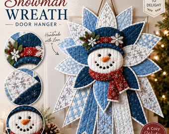 May include: A quilted snowman wreath door hanger featuring a central snowman face with a carrot nose, wearing a dark blue hat and a red scarf. The wreath is constructed from layered, star-shaped fabric petals in shades of blue and white.