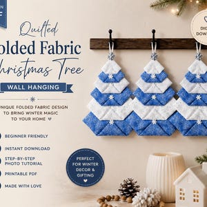 May include: Three quilted folded fabric Christmas tree wall hangings in blue and white, featuring snowflake patterns and small white snowflake embellishments, suspended from a dark wooden rack with black hooks, presented as a digital PDF pattern.