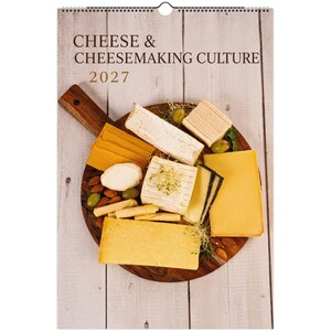 Op de afbeelding: Een wandkalender voor 2027 met de titel CHEESE & CHEESEMAKING CULTURE, voorzien van een houten serveerplank met diverse soorten kaas, waaronder gele cheddarschijfjes, witte blokken en partjes, gegarneerd met groene olijven en amandelen.
