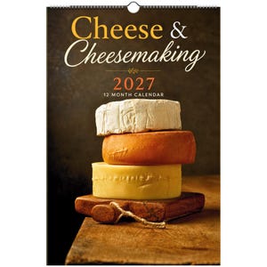 Pode incluir: Um calendário de parede de 12 meses para 2027 intitulado Cheese & Cheesemaking, apresentando uma pilha de três queijos redondos em branco, laranja e amarelo sobre uma tábua de madeira contra um fundo escuro, com encadernação de arame no topo.