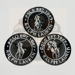 May include: Three circular black embroidered patches featuring the white Polo Ralph Lauren logo and text. Each patch displays a polo player on horseback with the text POLO RALPH LAUREN and EST. 1967 arranged in a circular border around the central graphic.