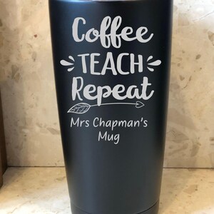 May include: A matte black stainless steel tumbler with a clear lid. The front features white text that reads Coffee TEACH Repeat with a decorative arrow graphic underneath, followed by the personalised text Mrs Chapman's Mug.