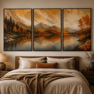 Peut inclure: Un ensemble de trois tableaux muraux représentant un paysage de montagnes, un lac calme et des arbres d'automne dans des tons orange, marron et doré. Les trois toiles rectangulaires sont encadrées de noir et disposées au-dessus d'un lit.