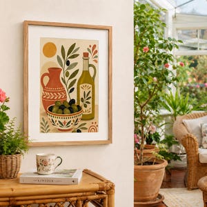 Op de afbeelding: Een ingelijste kunstdruk met een gestileerde illustratie van een terracotta kan, een fles olijfolie en een kom gevuld met groene en zwarte olijven. Het kunstwerk gebruikt een warm kleurenpalet met aardetinten, olijftakken en een zon.