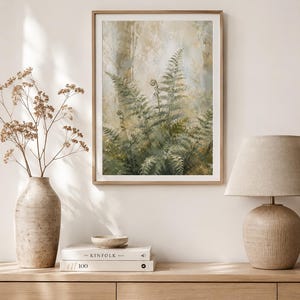 May include: A framed vertical wall art print featuring a detailed painting of green fern fronds in a forest setting with soft beige and muted earth tones. The artwork is displayed in a thin light wood frame with a white mat border.