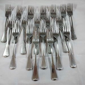 May include: A set of 18 silver forks with a simple, elegant design. The forks are arranged in a fan shape on a white surface.