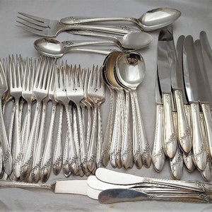 May include: A set of silverware, including forks, knives, and spoons, all with an ornate floral design. The silverware is made of silver and has a polished finish.