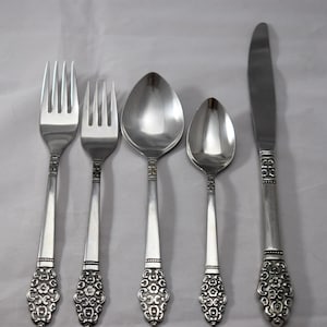 May include: Set of five silver-plated flatware pieces with ornate floral designs on the handles. The set includes a knife, fork, teaspoon, tablespoon, and a dinner fork.
