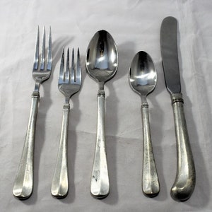 May include: A set of five silver-toned flatware pieces, including a fork, a knife, and three spoons. The handles are all made of a textured metal.