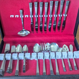 May include: A set of silver cutlery in a red velvet lined case. The set includes a variety of spoons, forks, and knives.