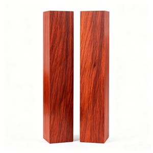 May include: Two tall, rectangular wooden blocks standing upright side by side. Each block features a deep reddish-brown color with a prominent, straight vertical wood grain pattern running along the length of the smooth, polished surfaces.
