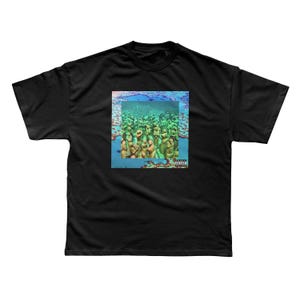 May include: A black short-sleeve t-shirt featuring a square graphic print on the chest. The image depicts a group of green statues submerged underwater, surrounded by blue and coral-colored textures, with a small Parental Advisory label.