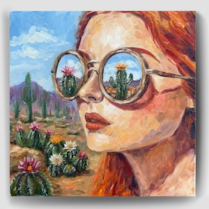 Puede incluir: Una pintura al óleo que representa a una persona con cabello rojizo usando gafas de sol redondas. Los lentes reflejan un paisaje desértico con cactus. El fondo muestra una escena del desierto con cactus verdes y flores rosas y blancas.
