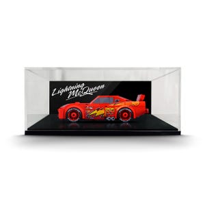 May include: A red toy race car model featuring the number 95, a yellow lightning bolt graphic, and Lightyear tire branding, enclosed in a clear rectangular display case with a black base and the text Lightning McQueen on the back panel.
