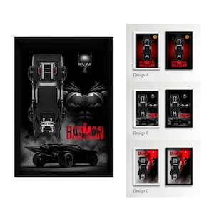 Puede incluir: Un póster enmarcado con la ilustración de la película The Batman. El diseño muestra un coche negro desde una perspectiva cenital, una vista lateral del vehículo y la silueta del personaje. El texto THE BATMAN está impreso en letras rojas.