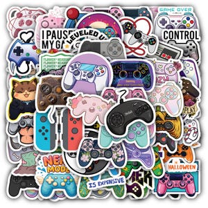 May include: A collection of vinyl stickers featuring various video game controllers, consoles, and gaming-themed text like "I paused my game," "Level up," "Game over," and "Control." The stickers display diverse colors, floral patterns, and cartoon designs.