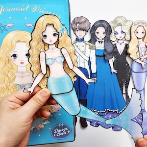 Könnte beinhalten: Ein Set aus Papierpuppen mit einer Meerjungfrau mit langem blonden Haar und blauem Schwanz, einem Prinzen in weißer Uniform und drei weiteren Figuren in blauen, schwarzen und meerjungfrauenartigen Outfits. Dazu gehört eine blaue Mappe mit Daisys Closet.