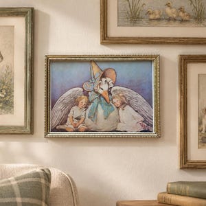 May include: A rectangular framed print featuring a central illustration of a large white goose with wings spread, wearing a blue bonnet and bow, flanked by two small children. The artwork is surrounded by other framed nature and portrait prints.
