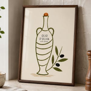 Op de afbeelding: Een ingelijste kunstdruk met een lijntekening van een olijfolie-amfoor met een oranje stop. De tekst luidt OLIO D'OLIVA EXTRA VERGINE. Een groene olijftak met twee zwarte olijven is aan de rechterkant van het vat afgebeeld.