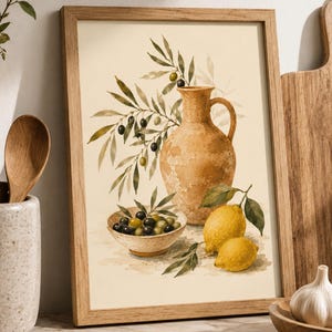 Op de afbeelding: Een ingelijste kunstdruk met een aquarelillustratie van een beige keramische kan, een klein schaaltje gevuld met groene en zwarte olijven, en twee gele citroenen. Olijftakken met bladeren steken uit achter de kan op een crèmekleurige achtergrond.