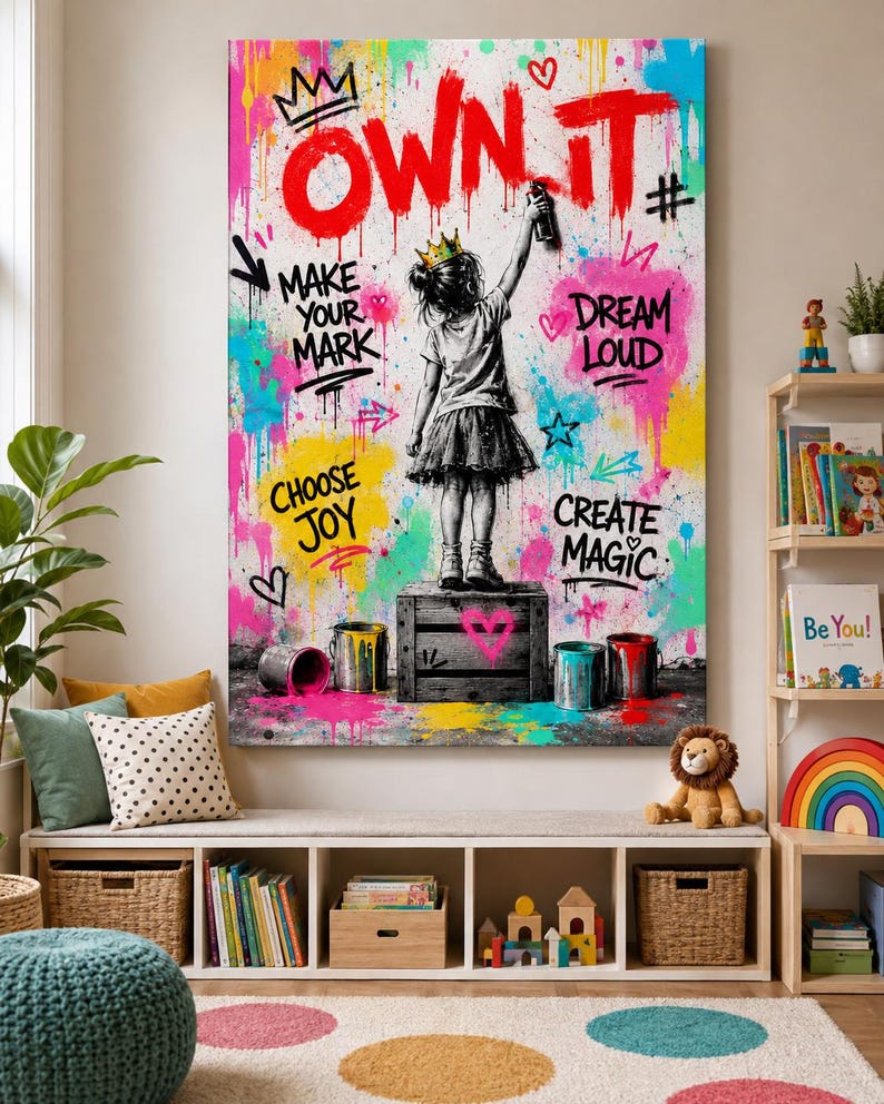 May include: A vertical wall art print featuring a black and white illustration of a child wearing a crown and standing on a crate, spray painting the text OWN IT in red. The background is filled with colorful paint splatters and phrases.