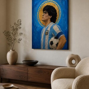 May include: A rectangular canvas wall art piece featuring an oil painting of a soccer player with dark curly hair, wearing a light blue and white striped jersey, holding a soccer ball, set against a vibrant blue background with a gold halo.