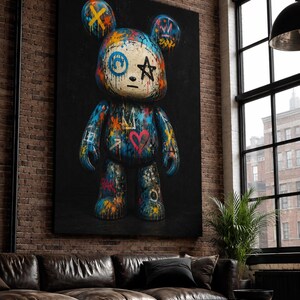 Op de afbeelding: Een grote verticale wandkunstprint met een gestileerd berenfiguur tegen een zwarte achtergrond. De beer is bedekt met kleurrijke graffiti-achtige verfspatten, een rood hart, een zwarte ster en diverse abstracte symbolen in blauw, oranje en geel.