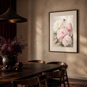 Puede incluir: Una l&aacute;mina de arte enmarcada que presenta un ramo de peon&iacute;as de color rosa suave y blanco en plena floraci&oacute;n. La obra de arte se muestra en un marco oscuro y fino, destacando los p&eacute;talos florales detallados y el follaje verde sobre un fondo claro.
