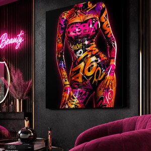 Puede incluir: Una pieza de arte mural rectangular que muestra una figura con un traje ajustado cubierto de arte urbano estilo grafiti. El dise&ntilde;o incluye salpicaduras, goteos y texto en colores rosa, naranja y amarillo vibrantes sobre un fondo negro.