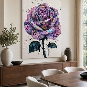 Puede incluir: Un gran cuadro rectangular de pared que muestra una rosa morada central cubierta de coloridos grafitis, etiquetas, s&iacute;mbolos y salpicaduras. La rosa tiene un tallo verde oscuro y dos hojas sobre un fondo blanco con gotas de pintura negra.
